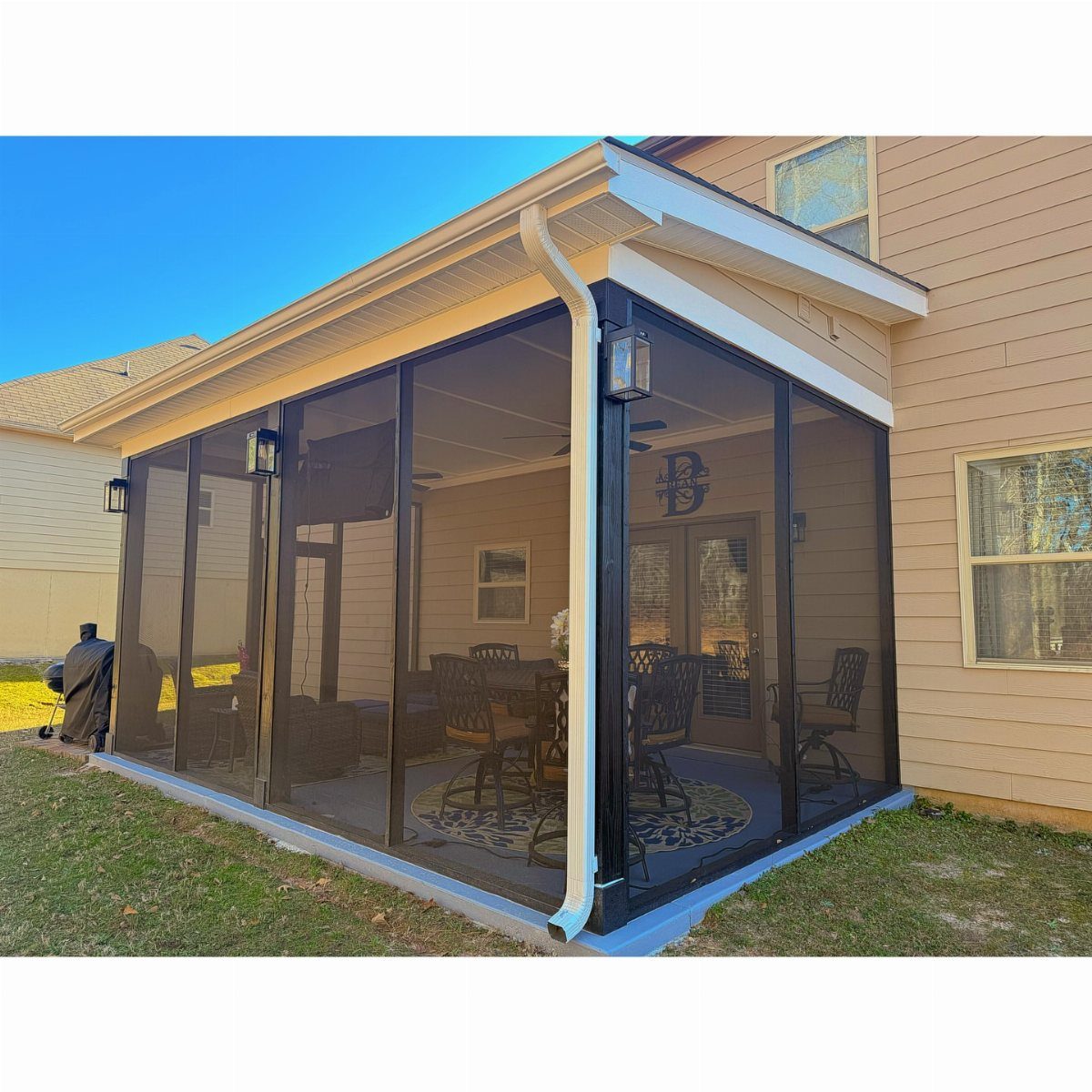 A screened-in covered patio with dining and lounge furniture attached to a tan house.