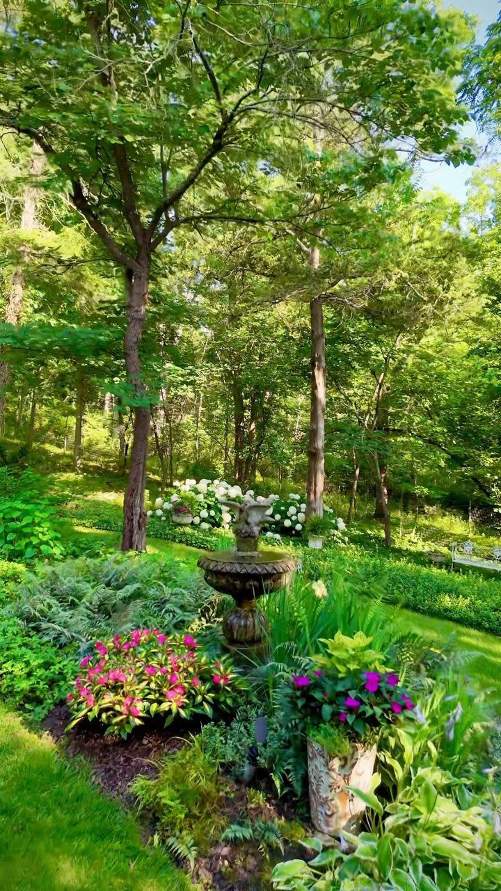 Backyard with Trees: 10 Layouts for Shade, Privacy and Outdoor Living 2 Lush shade garden with a stone fountain, pink flowers, and ferns under tall green trees.
