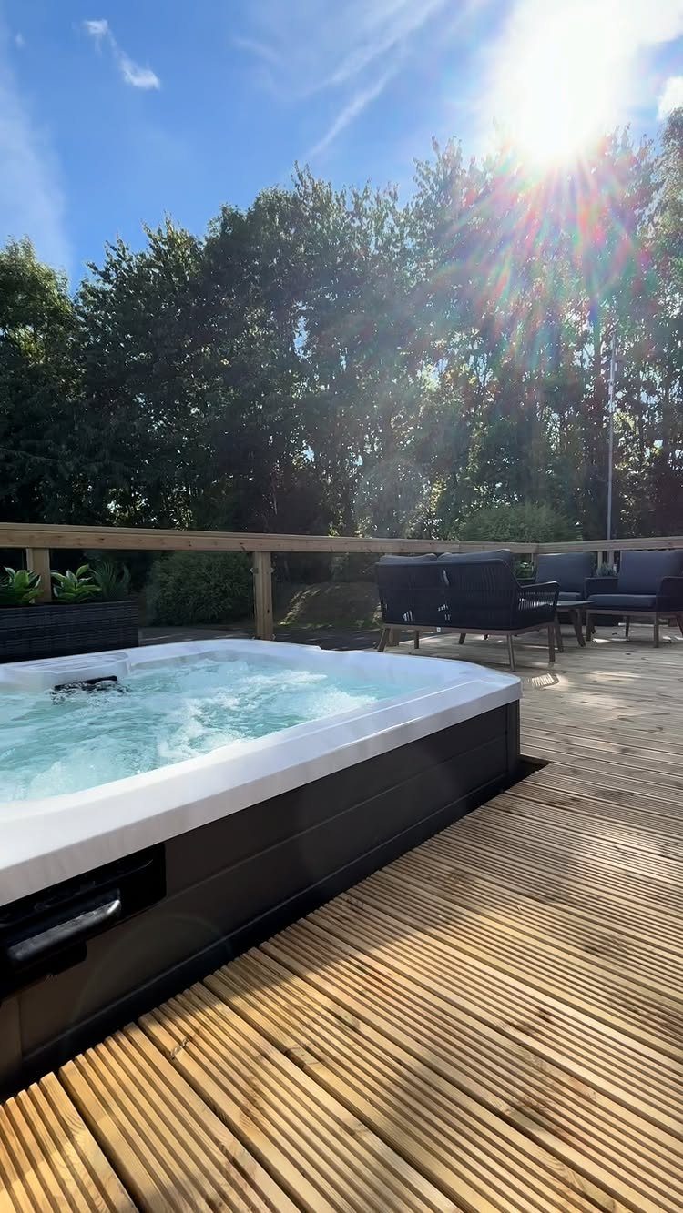 A white hot tub with bubbling water installed on a wooden outdoor deck.