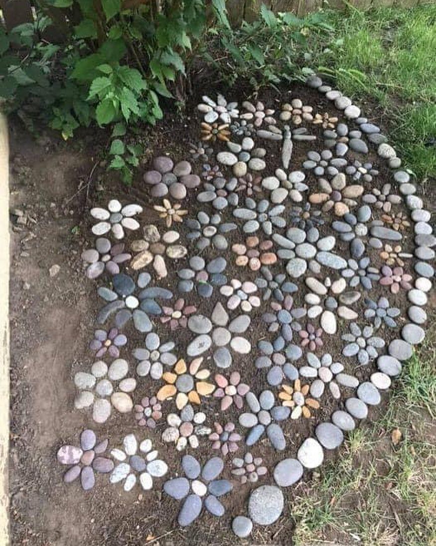 Smooth multi-colored stones arranged on the ground in various flower shapes and patterns.