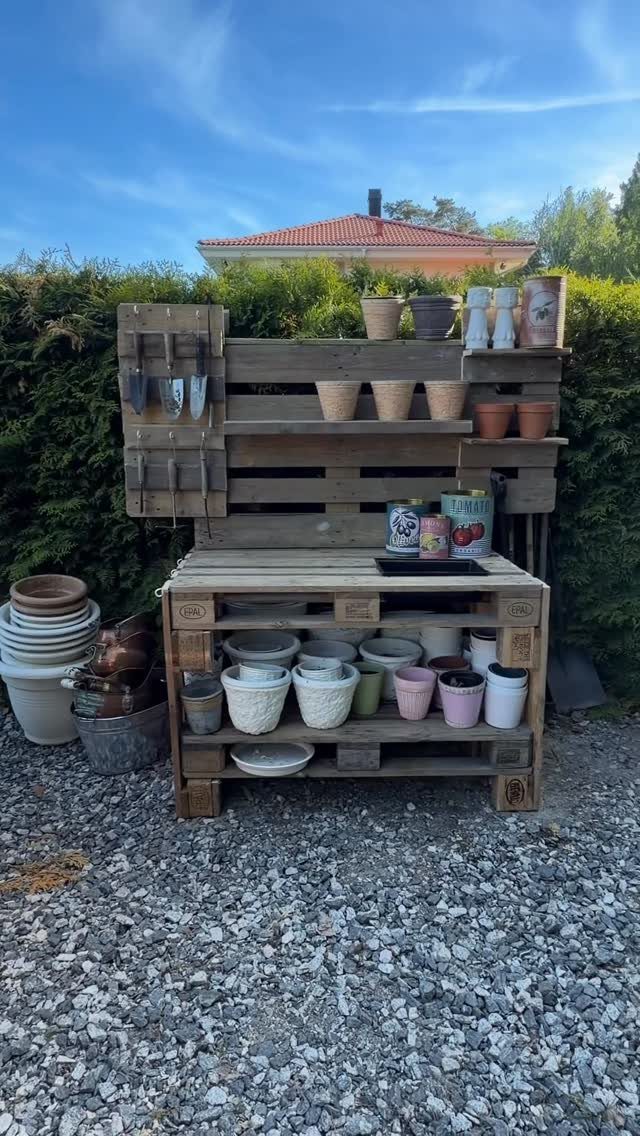 A wooden potting bench made from pallets holding many different ceramic and terracotta flower pots.