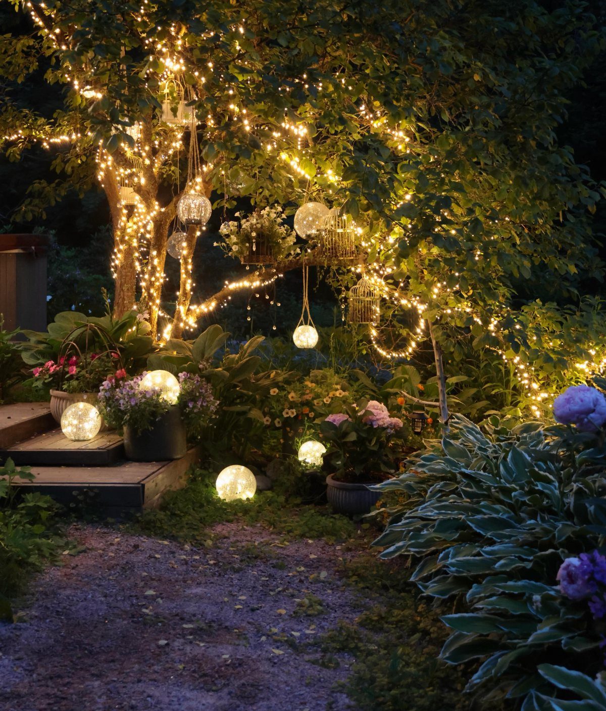 Glowing fairy lights and spherical lanterns illuminate a lush, dark garden filled with trees and flowers.