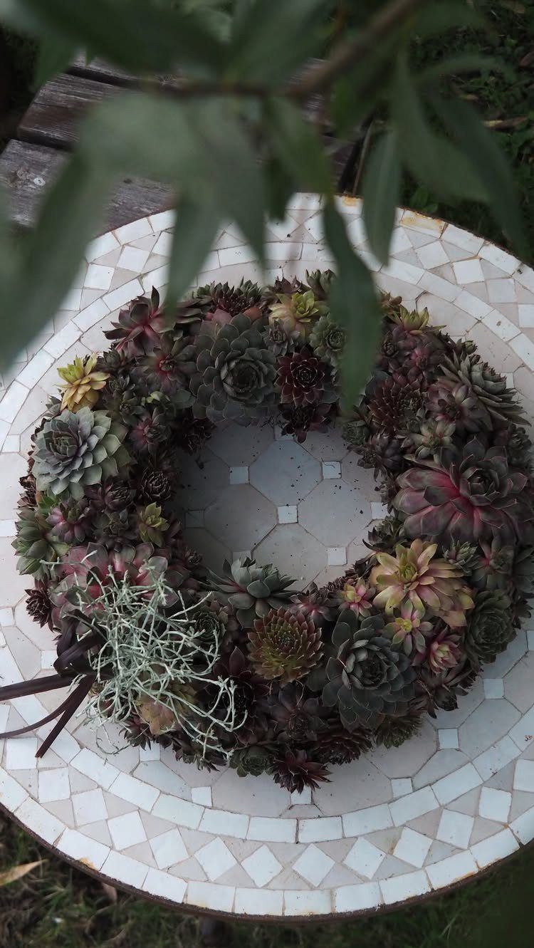 A circular wreath composed of various colorful succulent plants on a mosaic table.