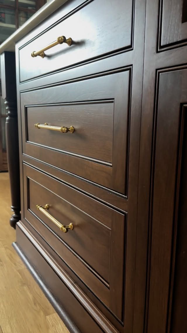 Dark wood kitchen cabinet drawers with modern gold horizontal bar pulls.