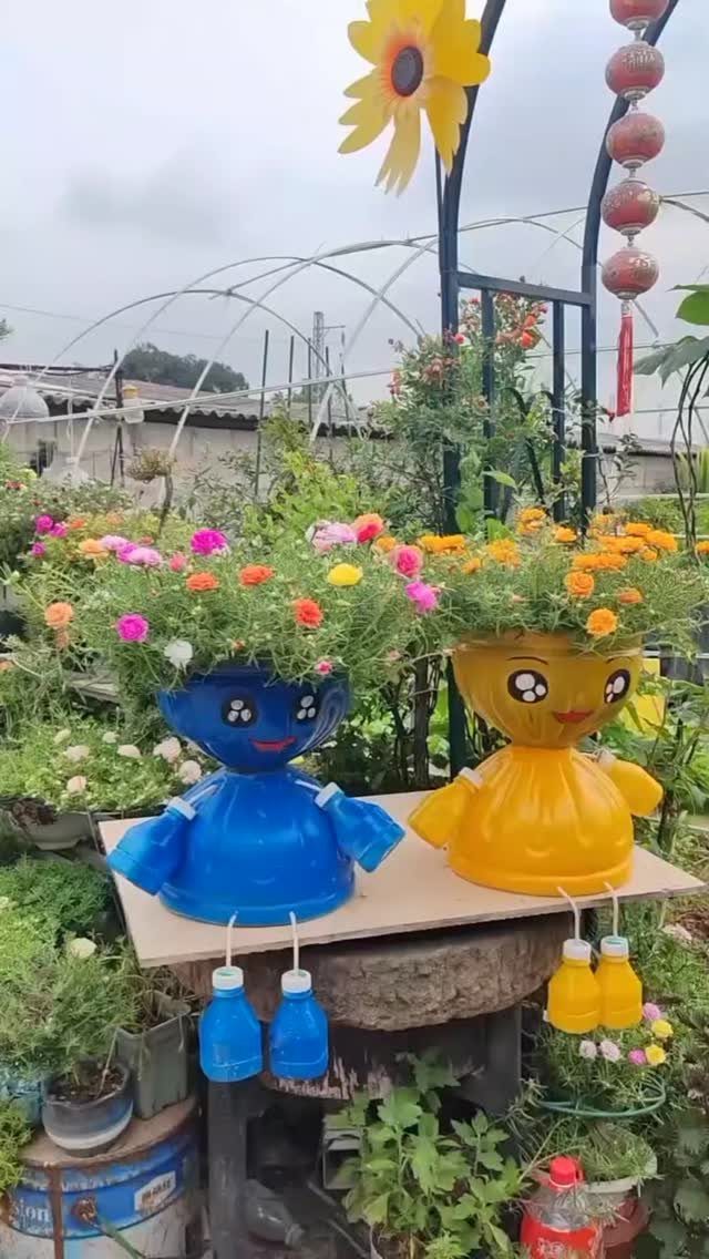 Two character-shaped plastic jug planters filled with colorful flowers sitting in a garden.